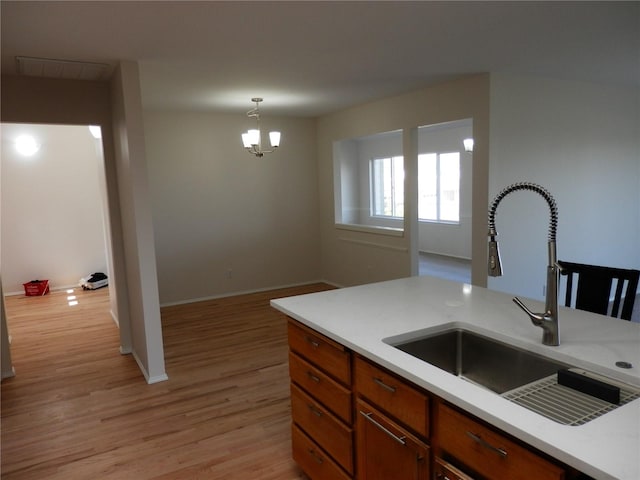 7819 Amethyst Loop NW, Silverdale, WA 98383 - kitchen featuring a sink, light countertops, light wood-style floors, a chandelier, and brown cabinetry