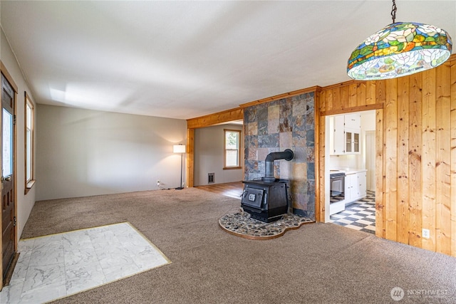 595 Division St, Manson, WA 98831 - unfurnished living room featuring a wood stove, wooden walls, and carpet flooring