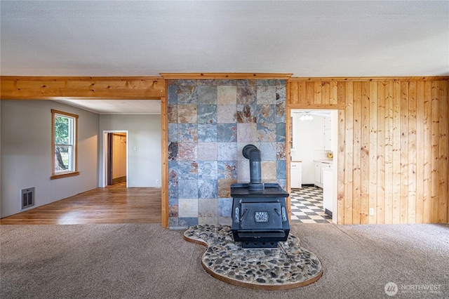 595 Division St, Manson, WA 98831 - unfurnished living room featuring a wood stove, carpet flooring, and wood walls