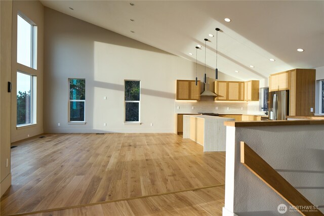 27208 J Ln, Ocean Park, WA 98640 - kitchen featuring freestanding refrigerator, high vaulted ceiling, wall chimney exhaust hood, light wood-style flooring, and hanging light fixtures