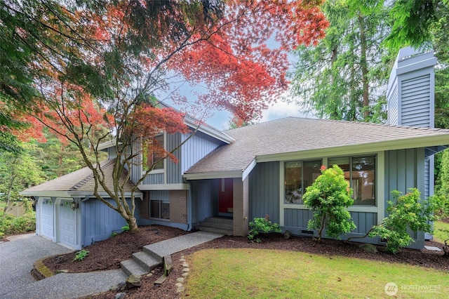 11423 NE 104th St, Kirkland, WA 98033 - tri-level home with a front lawn, a chimney, board and batten siding, driveway, and roof with shingles