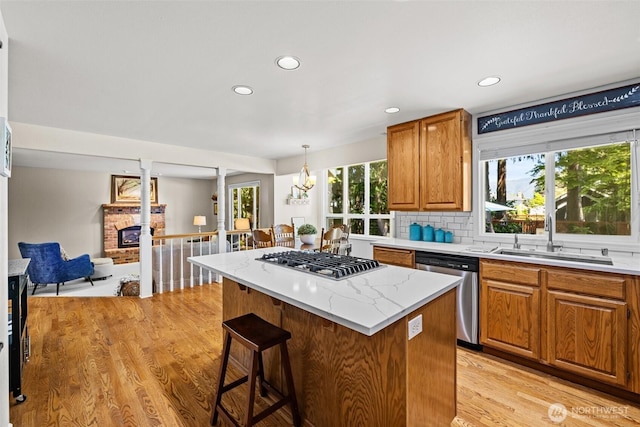 3924 Montgomery Ct, Mount Vernon, WA 98274 - kitchen with appliances with stainless steel finishes, a sink, a brick fireplace, light wood-style flooring, and a kitchen breakfast bar