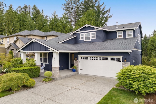 craftsman house with roof with shingles, driveway, covered porch, and board and batten siding