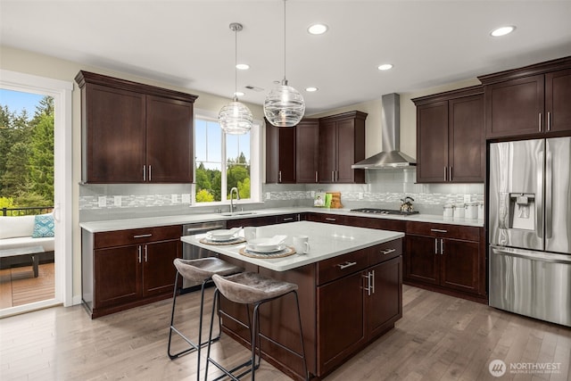 kitchen featuring stainless steel appliances, wall chimney exhaust hood, healthy amount of natural light, light countertops, and recessed lighting