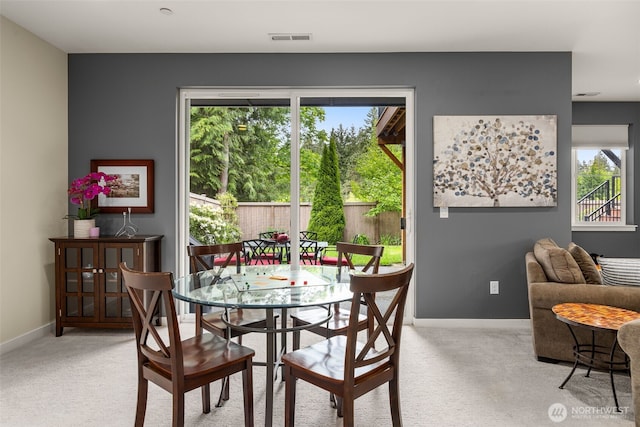 dining area with light carpet, plenty of natural light, and baseboards