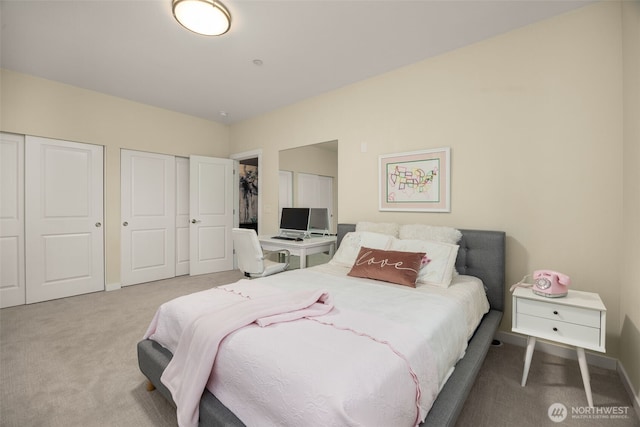 carpeted bedroom with two closets and baseboards