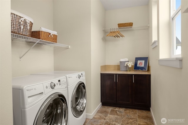 washroom with baseboards, washing machine and clothes dryer, and stone finish floors