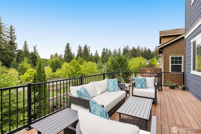 wooden terrace with an outdoor living space and a view of trees