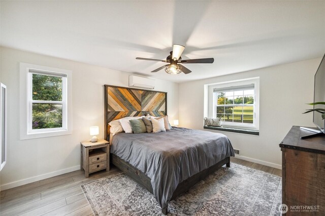 4279 H Street Rd, Blaine, WA 98230 - bedroom with a wall unit AC, multiple windows, baseboards, and light wood-style flooring