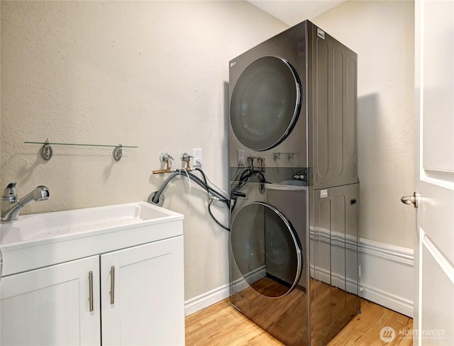 26309 187th Ct SE, Covington, WA 98042 - washroom featuring stacked washing machine and dryer, light wood finished floors, and cabinet space