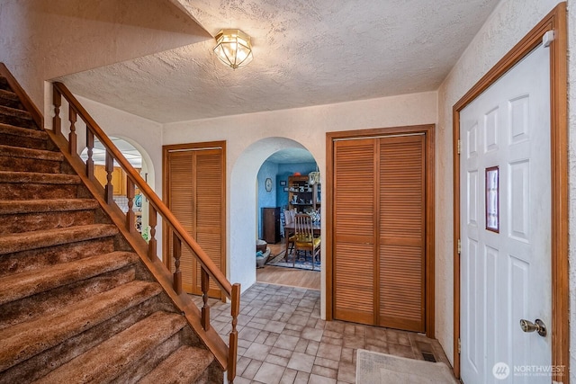 517 Marginal Way, Quincy, WA 98848 - entryway with arched walkways, stairs, a textured ceiling, brick patterned flooring, and a textured wall