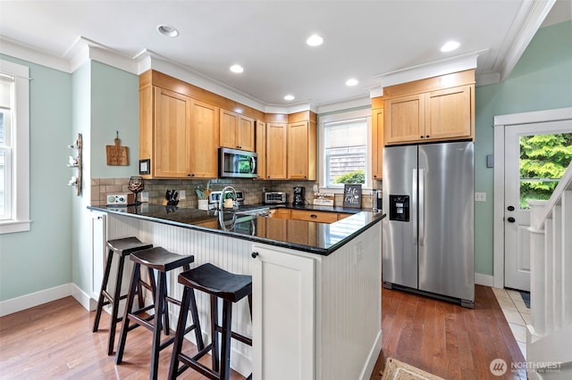 251 Meriweather St, Pacific Beach, WA 98571 - kitchen featuring appliances with stainless steel finishes, crown molding, a peninsula, dark countertops, and light wood-style flooring