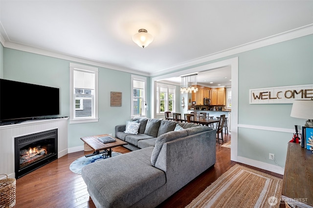 251 Meriweather St, Pacific Beach, WA 98571 - living area with ornamental molding, wood finished floors, a glass covered fireplace, a chandelier, and baseboards