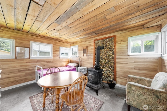 6709 E I St, Tacoma, WA 98404 - dining room with wood ceiling, wood walls, concrete flooring, a wood stove, and baseboards
