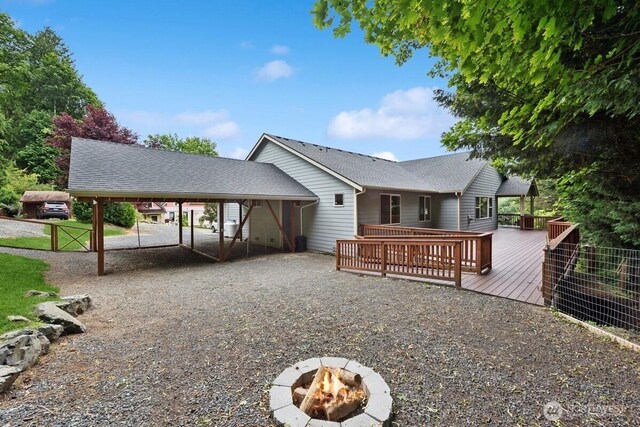 1310 Maple Ave, Snohomish, WA 98290 - back of house with an outdoor fire pit, a carport, a wooden deck, and driveway