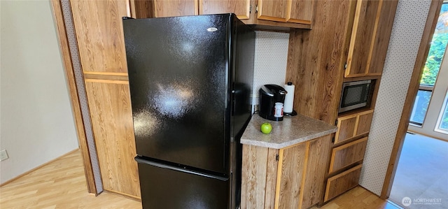 82 Marjory Ln, Sequim, WA 98382 - kitchen featuring freestanding refrigerator, stainless steel microwave, light wood finished floors, and brown cabinets