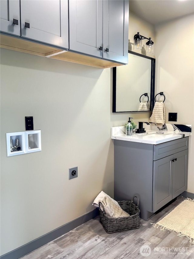 322 Fathom St NE, Ocean Shores, WA 98569 - laundry room with electric dryer hookup, cabinet space, wood finished floors, hookup for a washing machine, and baseboards