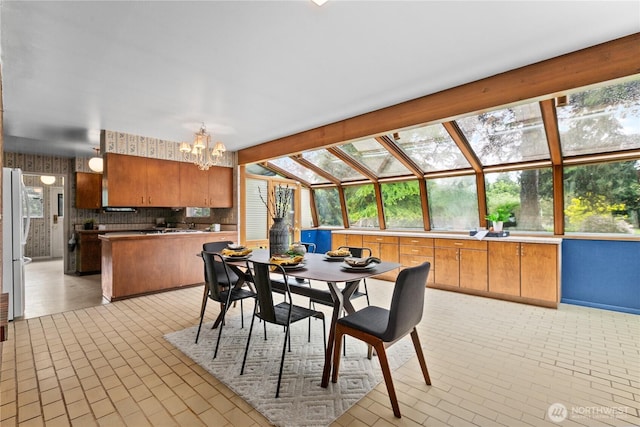 907 Baker St, Bellingham, WA 98225 - dining room featuring a chandelier, vaulted ceiling, brick patterned floors, and plenty of natural light