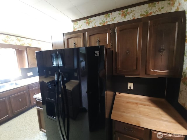 116 W 4th, Port Angeles, WA 98362 - kitchen with black fridge with ice dispenser, wallpapered walls, dark brown cabinetry, and butcher block counters