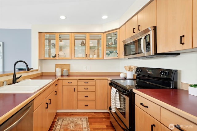 701 Galer St Unit 808, Seattle, WA 98109 - kitchen with stainless steel appliances, light brown cabinetry, a sink, wood finished floors, and glass insert cabinets