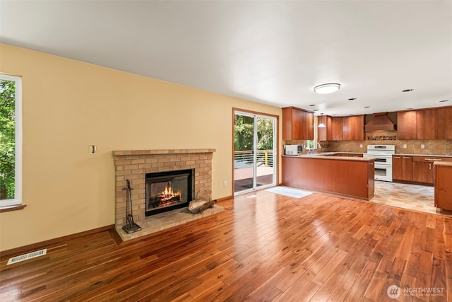 4528 SW 316th Pl, Federal Way, WA 98023 - kitchen with white stove, open floor plan, brown cabinets, light wood finished floors, and premium range hood