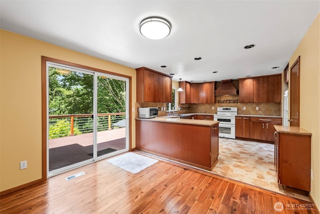 4528 SW 316th Pl, Federal Way, WA 98023 - kitchen featuring white appliances, custom exhaust hood, light wood-style flooring, a peninsula, and decorative backsplash