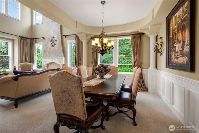 31045 219th Way SE, Black Diamond, WA 98010 - dining area with decorative columns, a chandelier, light colored carpet, a wainscoted wall, and plenty of natural light