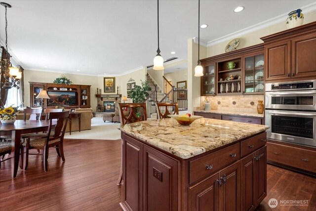 31045 219th Way SE, Black Diamond, WA 98010 - kitchen featuring double oven, a stone fireplace, decorative light fixtures, dark wood-style floors, and glass insert cabinets