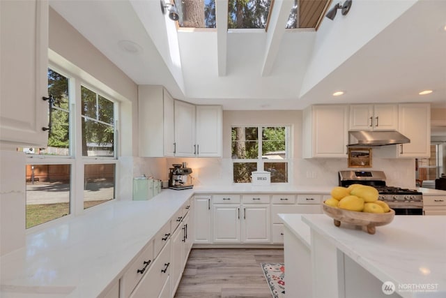 7611 176th Ave E, Bonney Lake, WA 98391 - kitchen featuring stainless steel gas range oven, under cabinet range hood, light countertops, light wood-style flooring, and tasteful backsplash