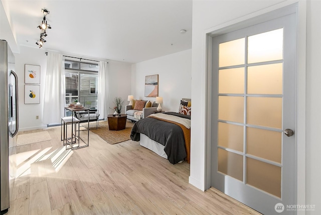 1414 12th Ave Unit 504, Seattle, WA 98122 - bedroom featuring light wood-style flooring, track lighting, multiple windows, and stainless steel refrigerator with ice dispenser