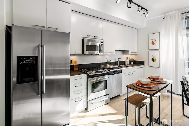 1414 12th Ave Unit 504, Seattle, WA 98122 - kitchen with appliances with stainless steel finishes, dark countertops, a sink, and white cabinets