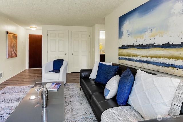 living room featuring wood finished floors, a textured ceiling, and baseboards