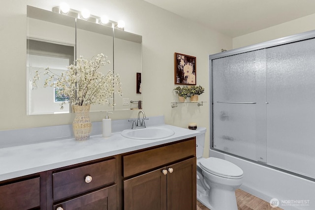 bathroom with vanity, toilet, shower / bath combination with glass door, and wood finished floors