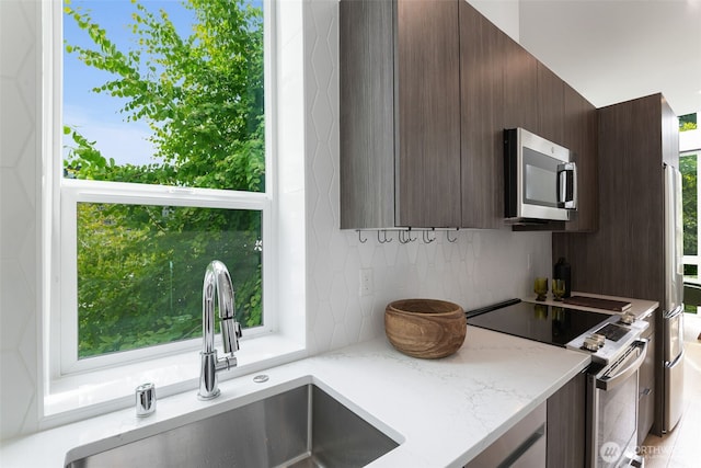 1406 21st Ave Unit A, Seattle, WA 98122 - kitchen featuring stainless steel appliances, a sink, decorative backsplash, dark brown cabinets, and light stone countertops