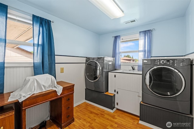 513 K St SW, Quincy, WA 98848 - washroom featuring cabinet space, light wood-type flooring, independent washer and dryer, and a wainscoted wall