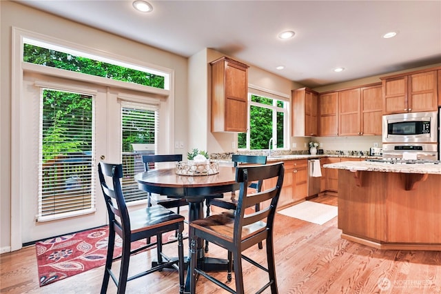 20524 73rd Dr SE, Snohomish, WA 98296 - kitchen with stainless steel appliances, light wood finished floors, recessed lighting, a kitchen bar, and light stone counters