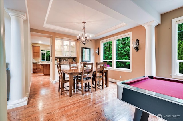 20524 73rd Dr SE, Snohomish, WA 98296 - dining space with ornate columns, light wood-style flooring, a tray ceiling, baseboards, and a chandelier