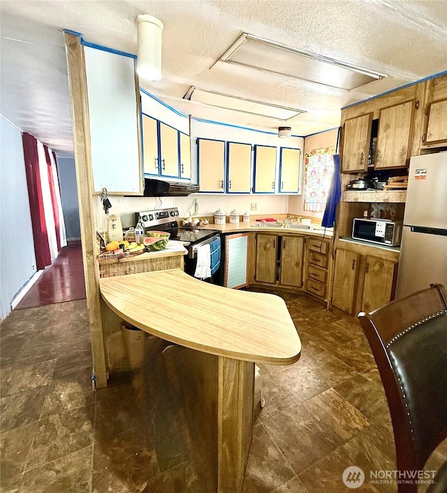 3333 SE 228th St Unit 105, Bothell, WA 98021 - kitchen with stainless steel appliances, under cabinet range hood, light countertops, a textured ceiling, and a peninsula