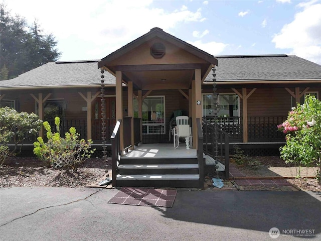 view of front of home with roof with shingles and a porch