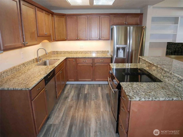 kitchen with stainless steel appliances, a sink, dark wood finished floors, light stone counters, and brown cabinetry