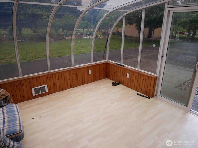 unfurnished sunroom featuring wooden walls and wood finished floors