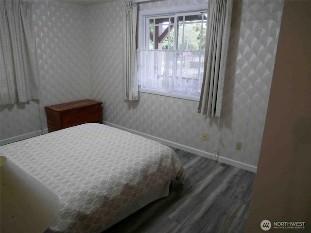 bedroom with wood finished floors, baseboards, and wallpapered walls
