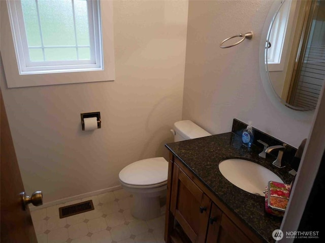 half bath featuring toilet, vanity, and baseboards