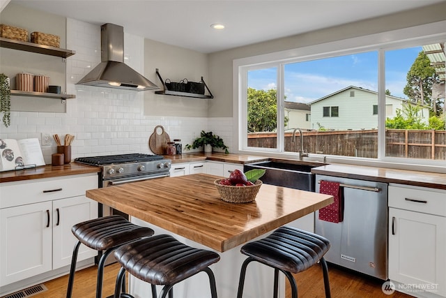9419 39th Ave S, Seattle, WA 98118 - kitchen featuring butcher block counters, wall chimney range hood, open shelves, a sink, and recessed lighting