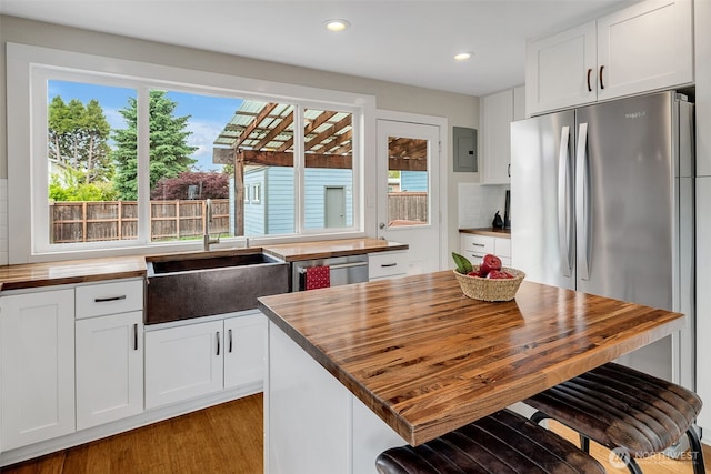 9419 39th Ave S, Seattle, WA 98118 - kitchen featuring butcher block counters, appliances with stainless steel finishes, a sink, white cabinetry, and recessed lighting