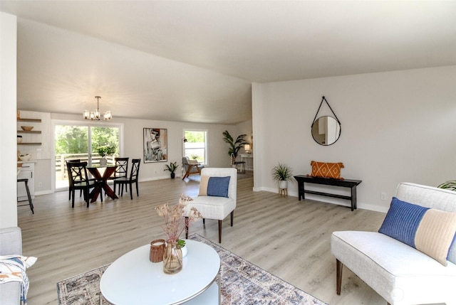 living area featuring a chandelier, plenty of natural light, light wood-style floors, baseboards, and lofted ceiling