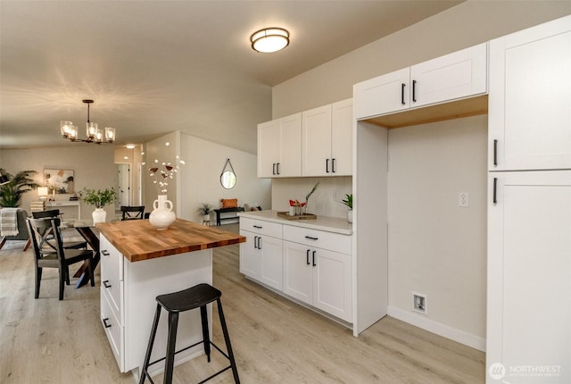 kitchen featuring wooden counters, light wood finished floors, and white cabinetry