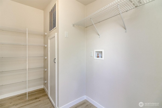 laundry area with washer hookup, light wood finished floors, and baseboards
