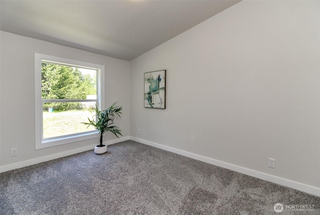 carpeted spare room with baseboards and vaulted ceiling