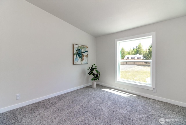 spare room featuring carpet, lofted ceiling, and baseboards